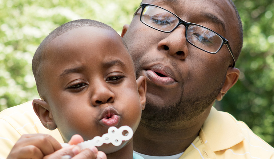 Father and young son blowing bubbles in the park.