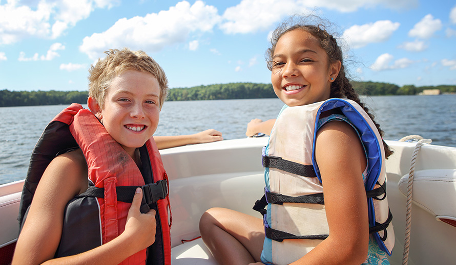 Niños contentos con salvavidas en un bote.