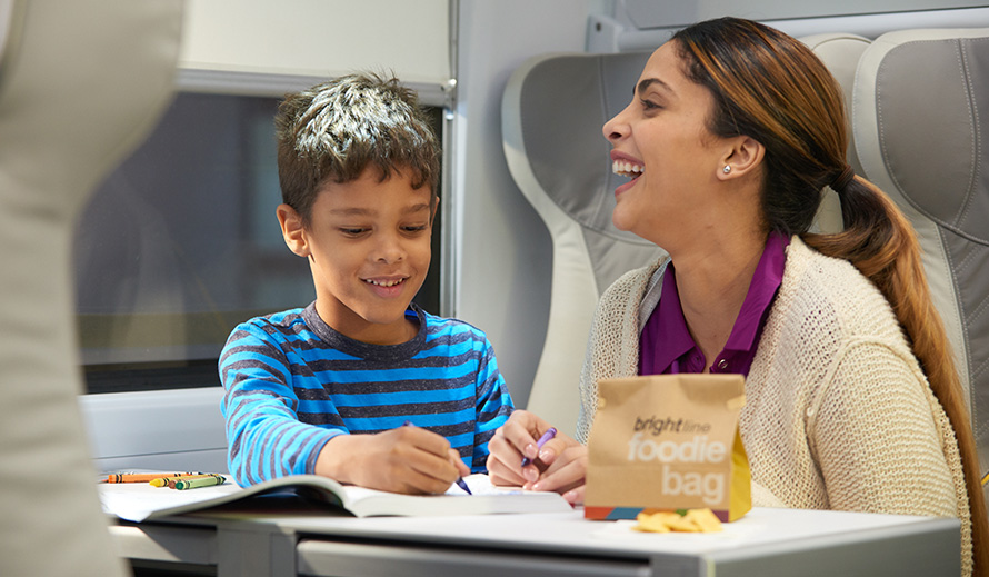 A boy and his mother enjoy activities aboard a Brightline train.