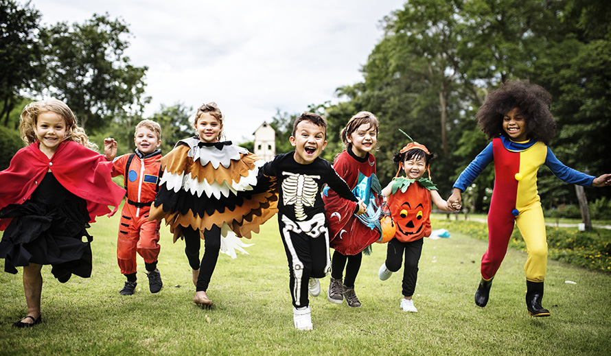Niños que corren en disfraces de Halloween.