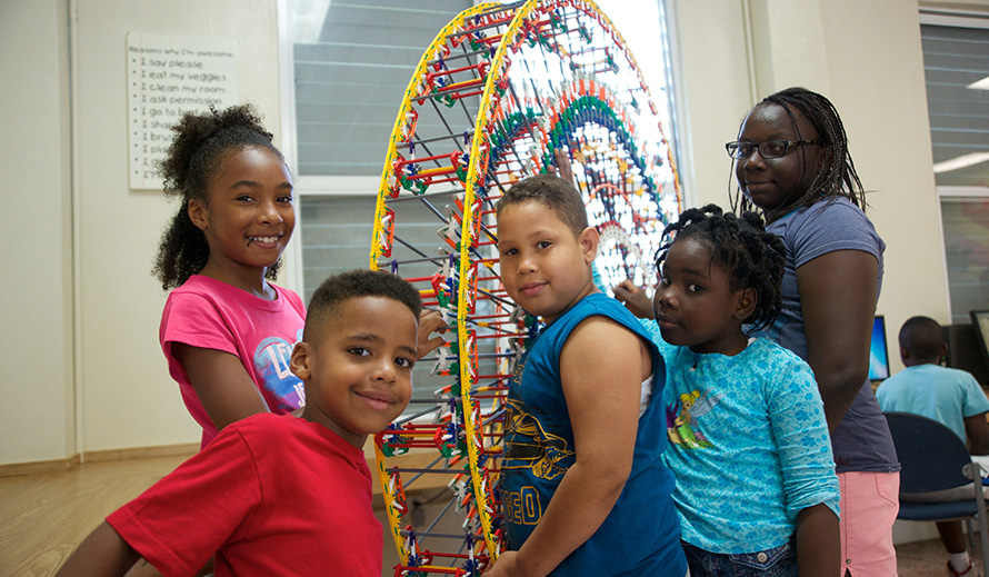 African-American children build a mini ferris wheel during summer camp. 