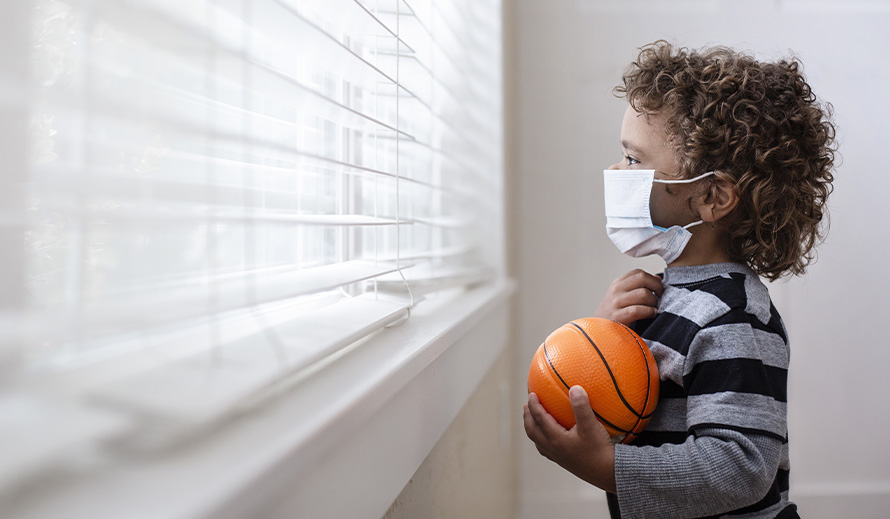  Un niño pequeño mira con nostalgia por la ventana durante la pandemia de coronavirus.