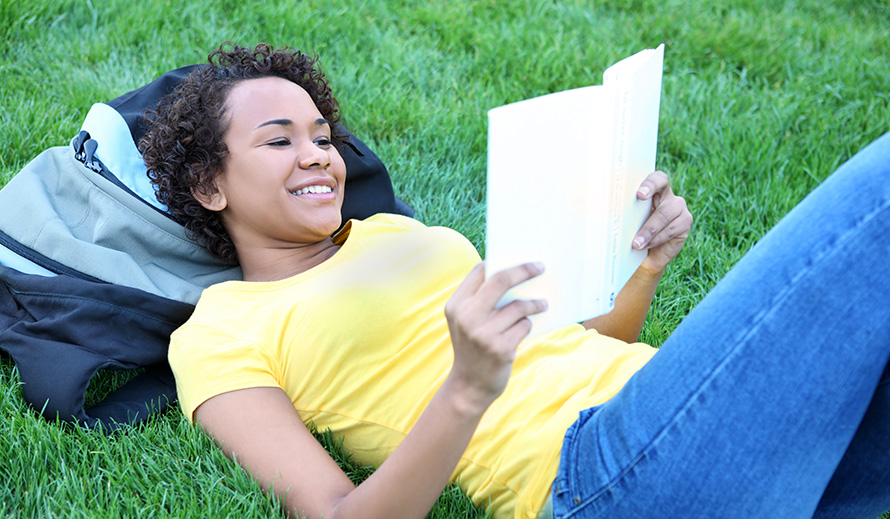 Teen girl happily reading a book.