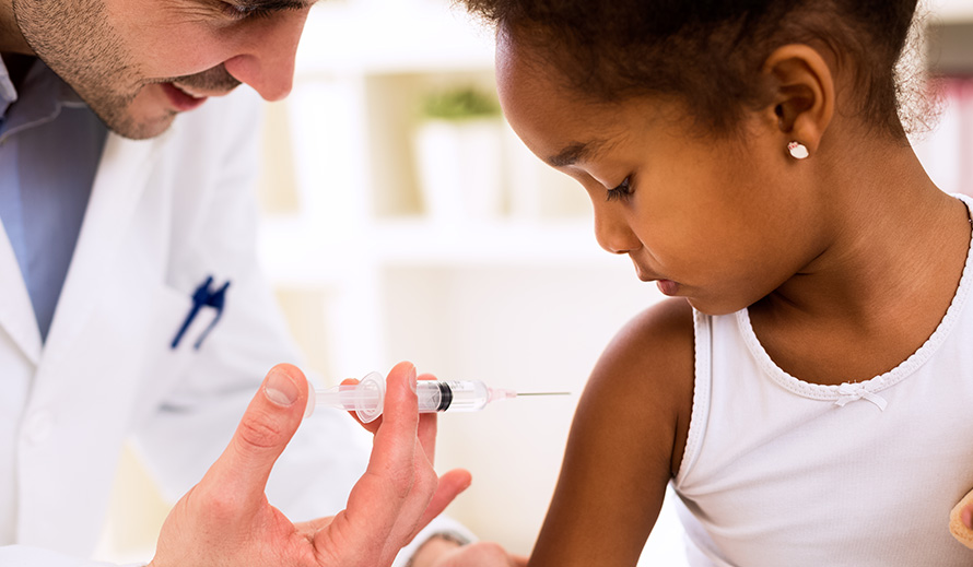 A pediatrician is about to give a vaccine shot to an African American girl. 