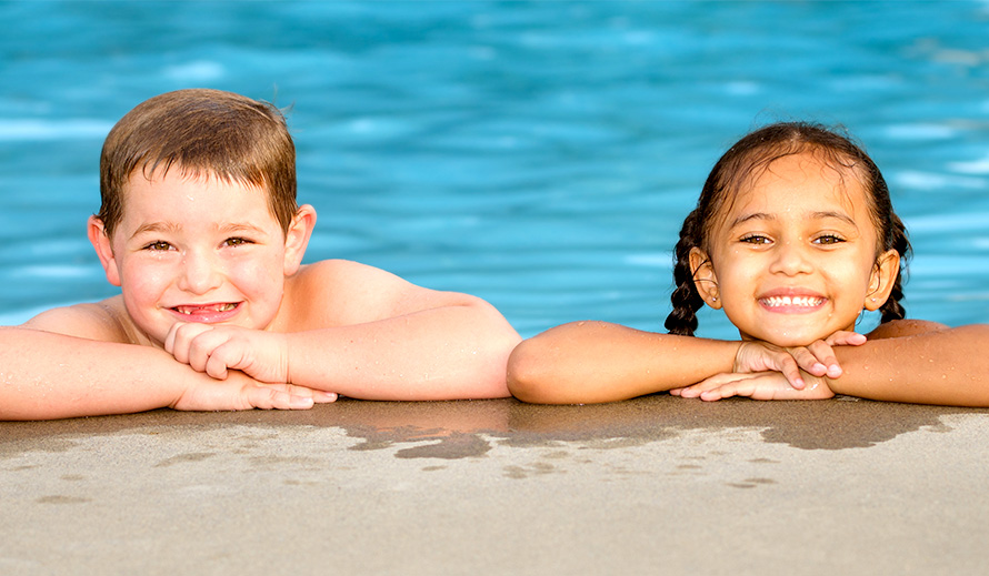 Boy and girl poolside smiling.