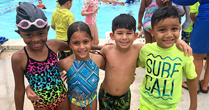 Niños sonrientes en traje de baño alrededor de una piscina