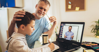 A father helps his son with his virtual studies. 