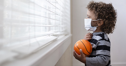  Un niño pequeño mira con nostalgia por la ventana durante la pandemia de coronavirus.