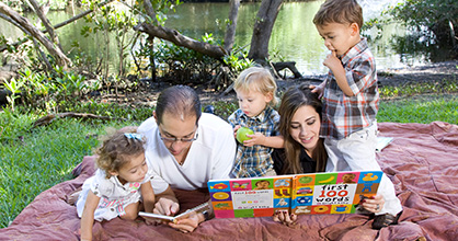 Familia leyendo sobre un manto en el parque.